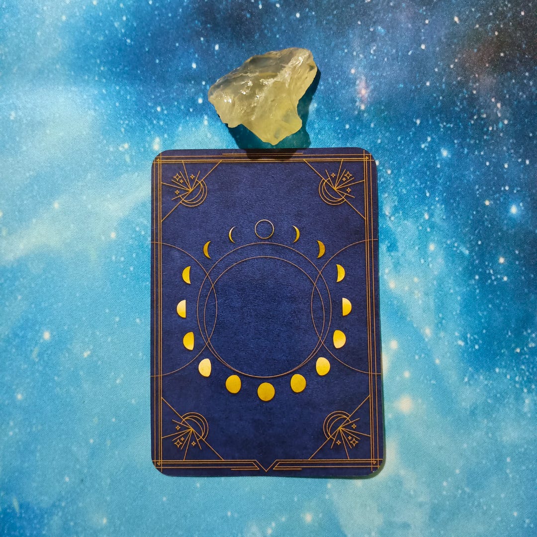 New Moon Magic: Your August 2025 Pick-a-Card Tarot Reading, pile 3 — citrine (yellow) stone and an oracle, face down on a starry blue background