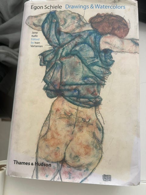Cover of Egon Schiele book by Thames and Hudson, featuring a drawing of a white woman with reddish brown hair from behind. She wears a teal blue loose top and has bare buttocks. The cover cuts out just below, at mid thigh Cover of Egon Schiele book by Thames and Hudson, featuring a drawing of a white woman with reddish brown hair from behind. She wears a teal blue loose top and has bare buttocks. The cover cuts out just below, at mid thigh
