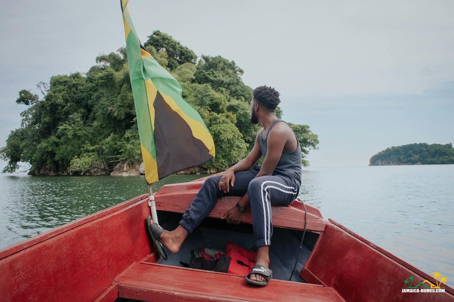 man sitting on boat with jamaican flag