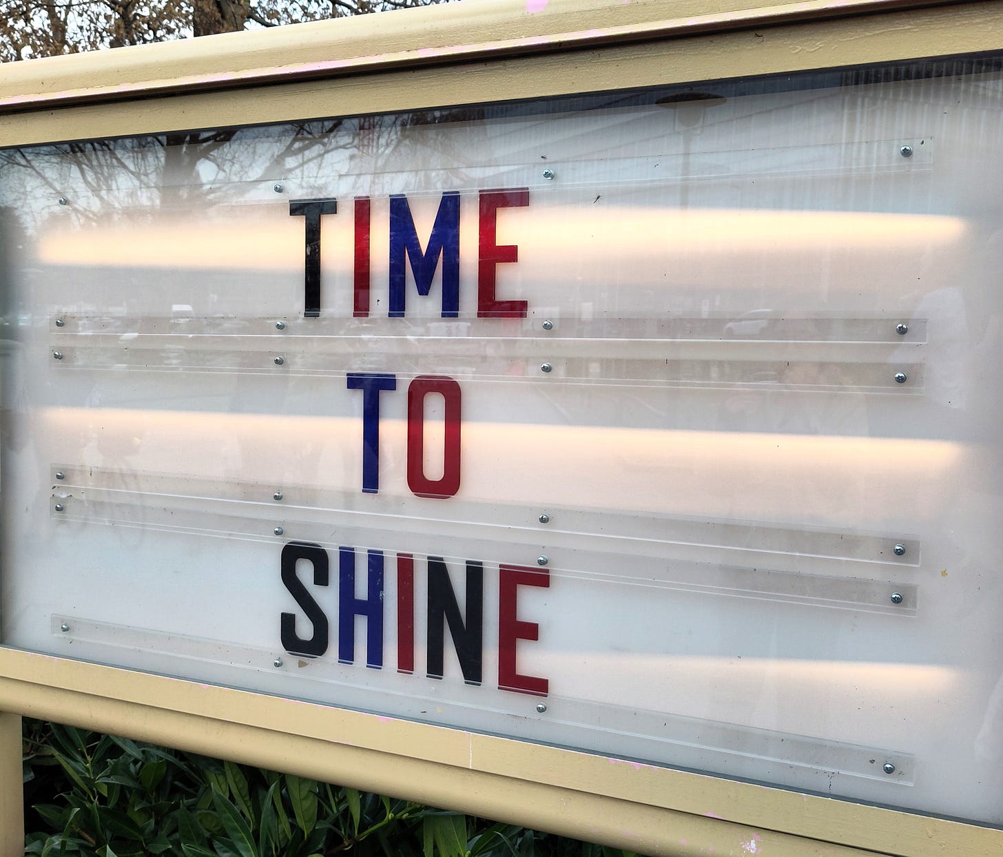 Insegna luminosa su cui si legge "Time to shine" in lettere maiuscole a colori alternati tra nero, rosso e blu