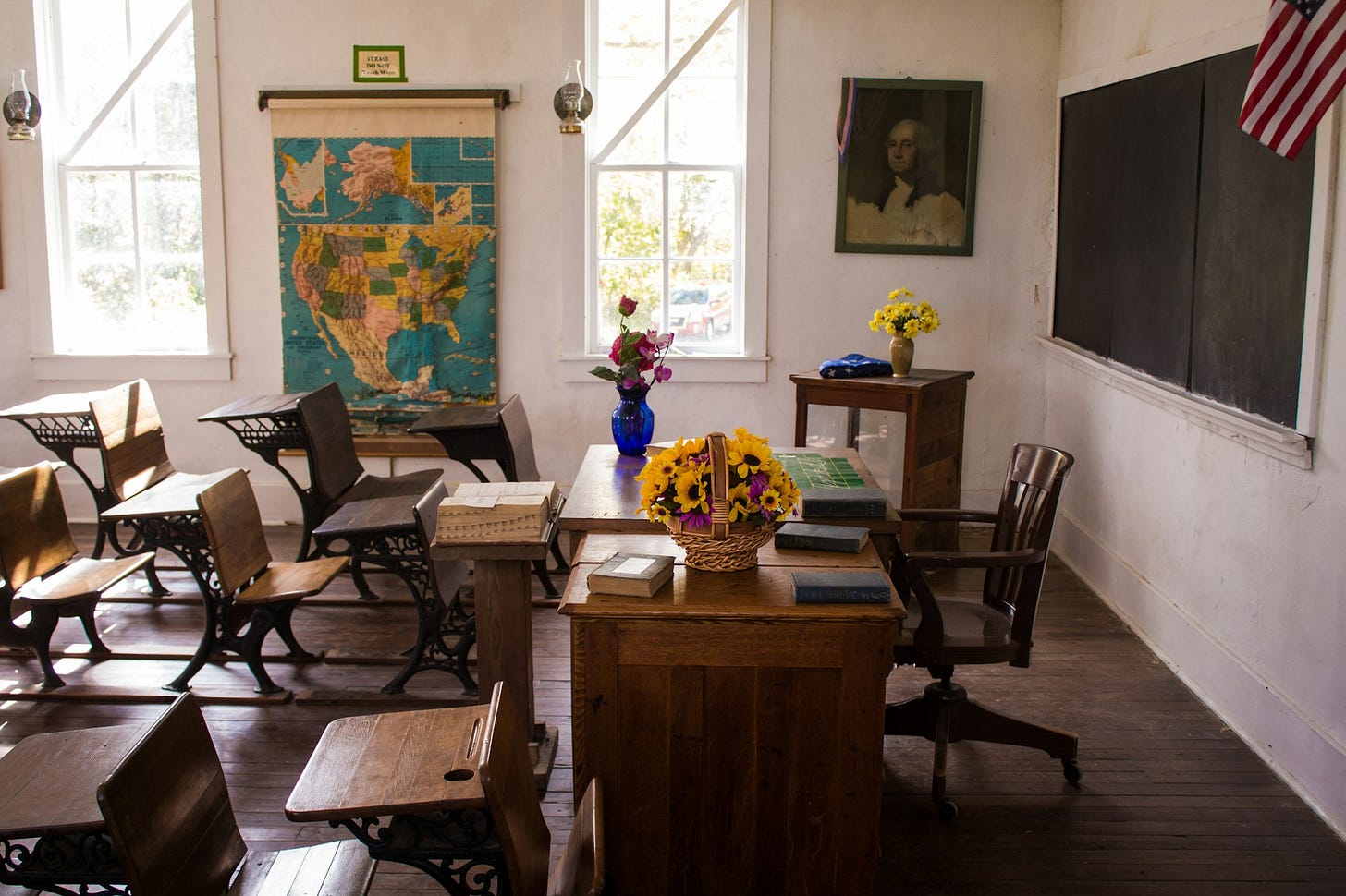 vacant white painted classroom with chairs, tables , and map on the wall vacant white painted classroom with chairs, tables , and map on the wall