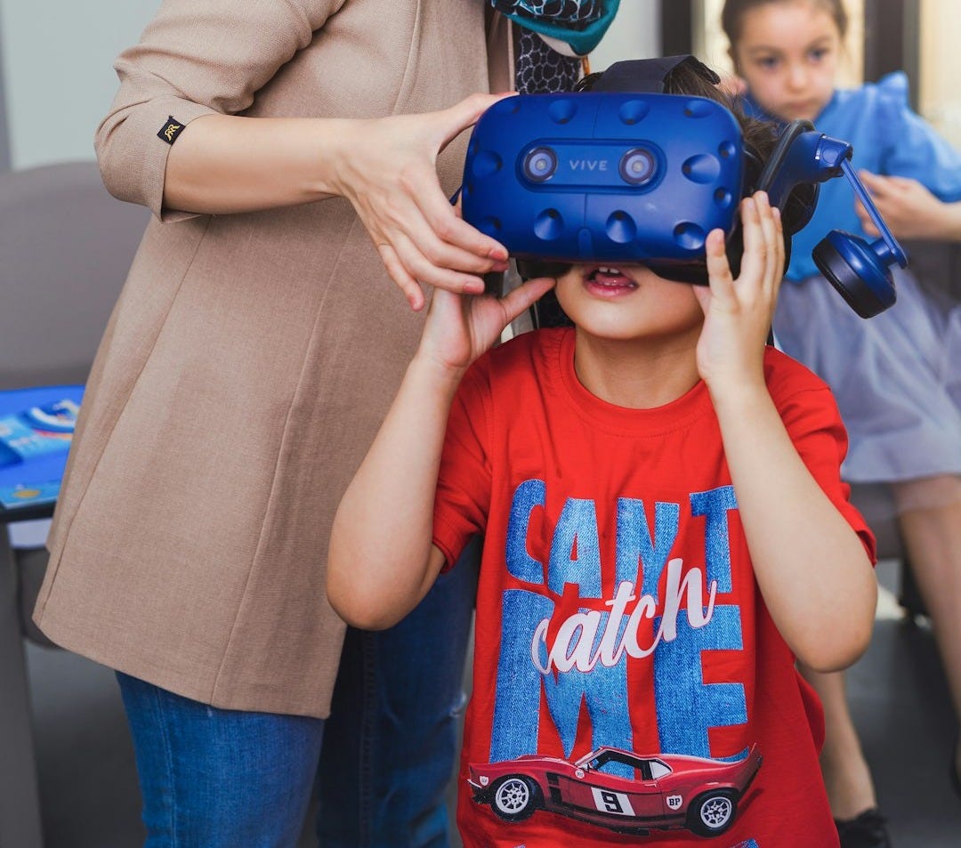 Woman helps child put on virtual reality headset. Woman helps child put on virtual reality headset.