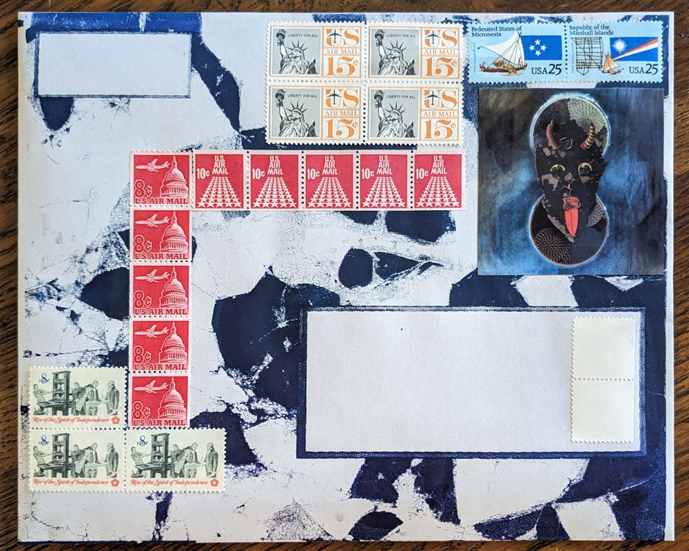 A blue and white marbled envelope is decorated with carefully arranged vintage U.S. stamps in red, blue, and orange hues. A striking cutout of a demonic face with glowing eyes and a protruding tongue sits in the top right corner.