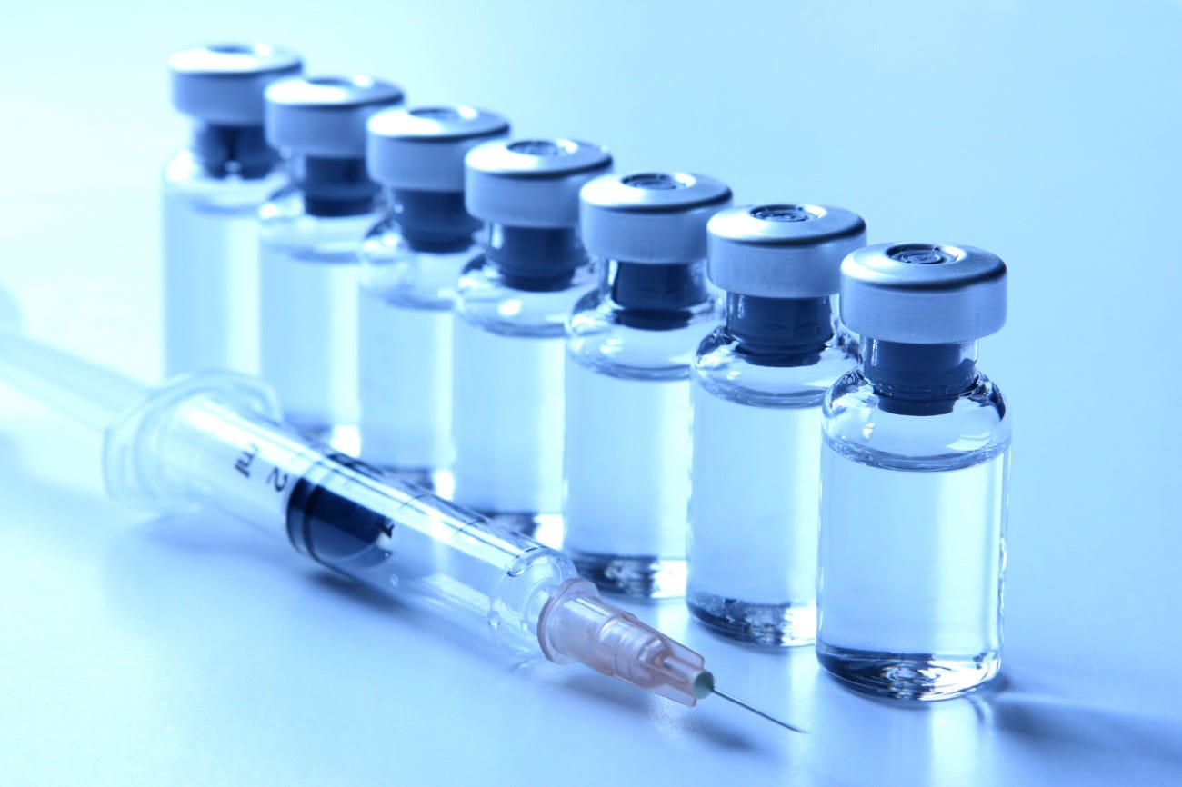 Rows of clear glass vaccine vials with rubber stoppers. Rows of clear glass vaccine vials with rubber stoppers.