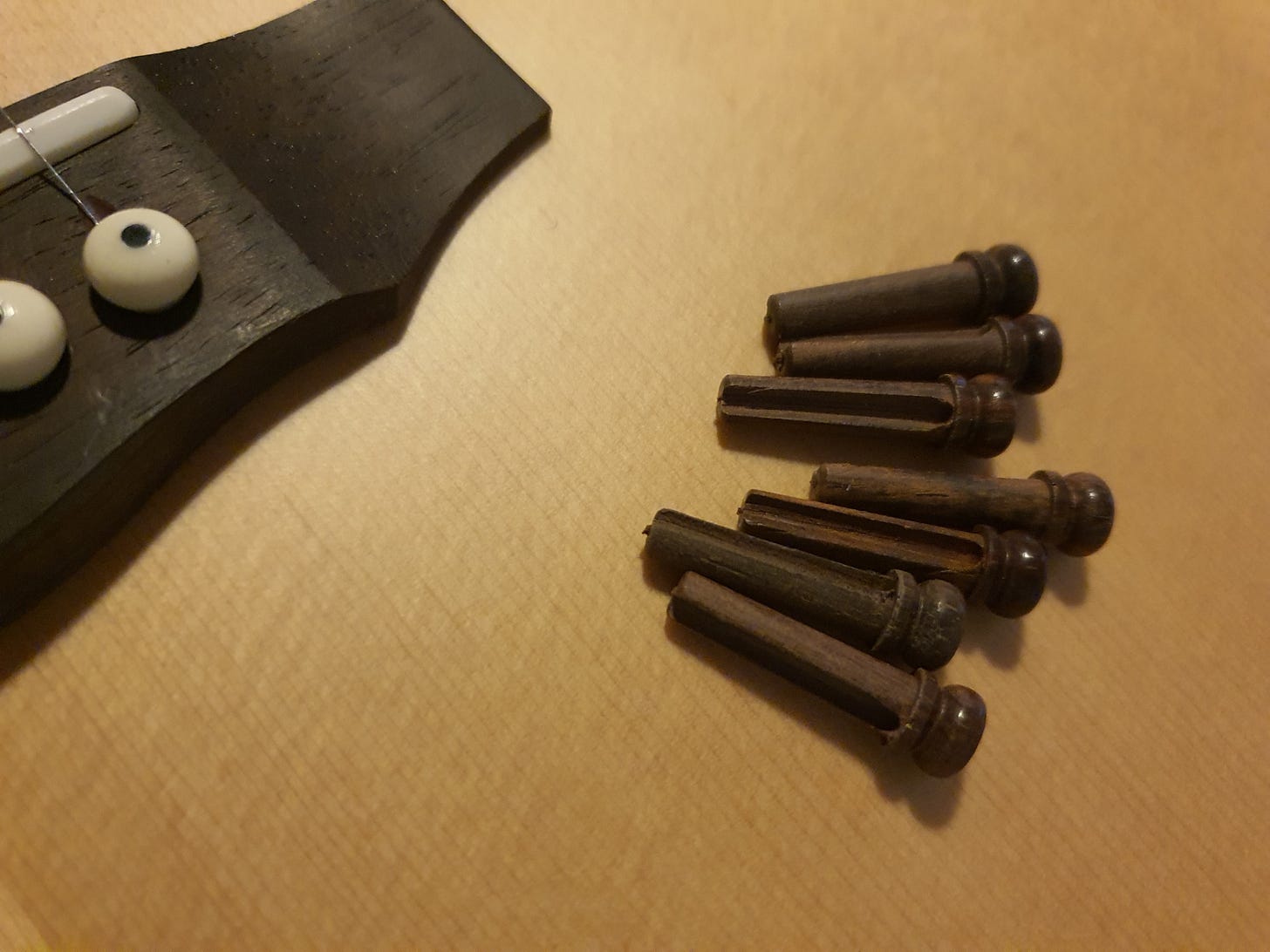 guitar top with loose bridge pins lying on top.