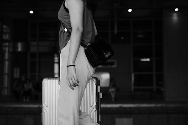 A woman walks away with a metal suitcase.