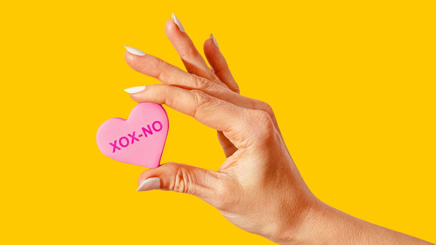 A hand holding up a candy heart saying "XOX-NO"