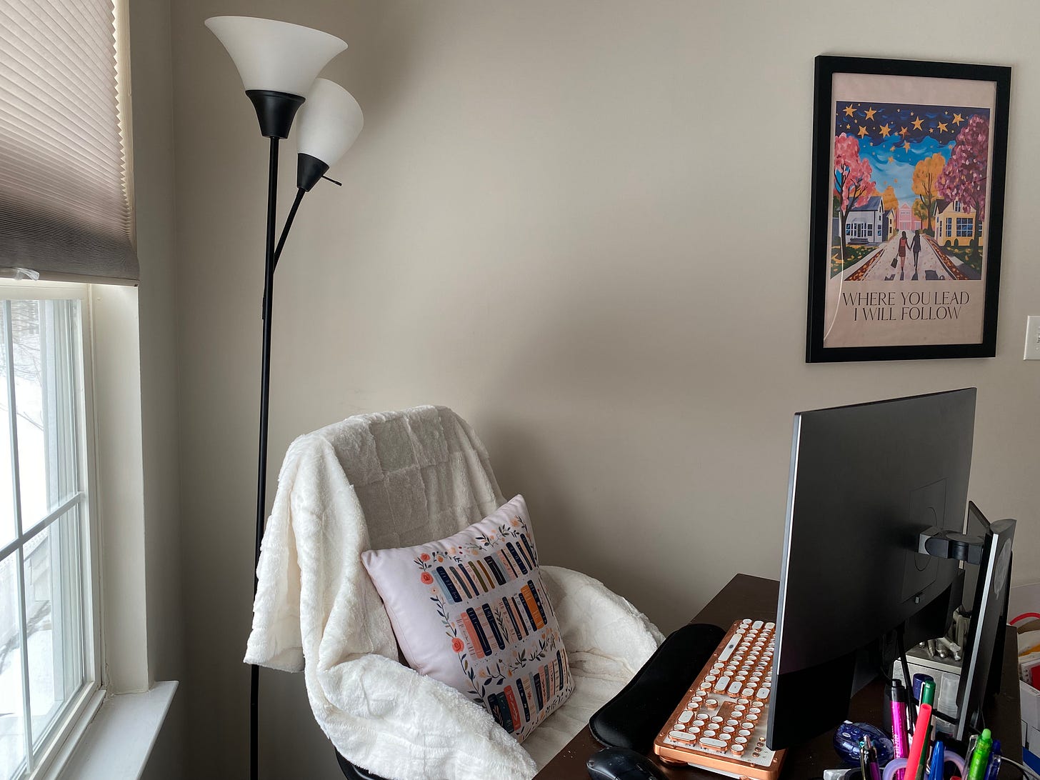 home office with desk chair with a book-themed pillow and a gilmore girls poster in the background