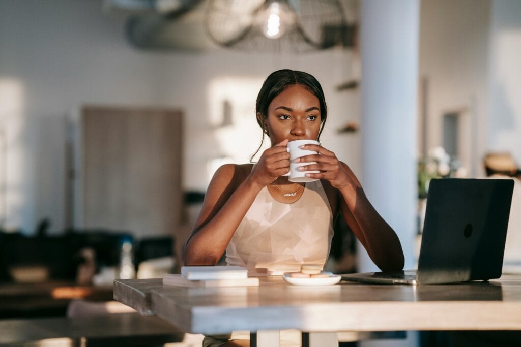 A woman taking a mindful coffee break at her desk to maintain calm and focus during work Une femme buvant un café assise à une table