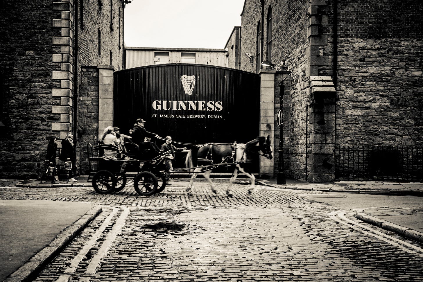 A horse-drawn carriage rides past the front gate to the Guiness Storehouse in Dublin, Ireland