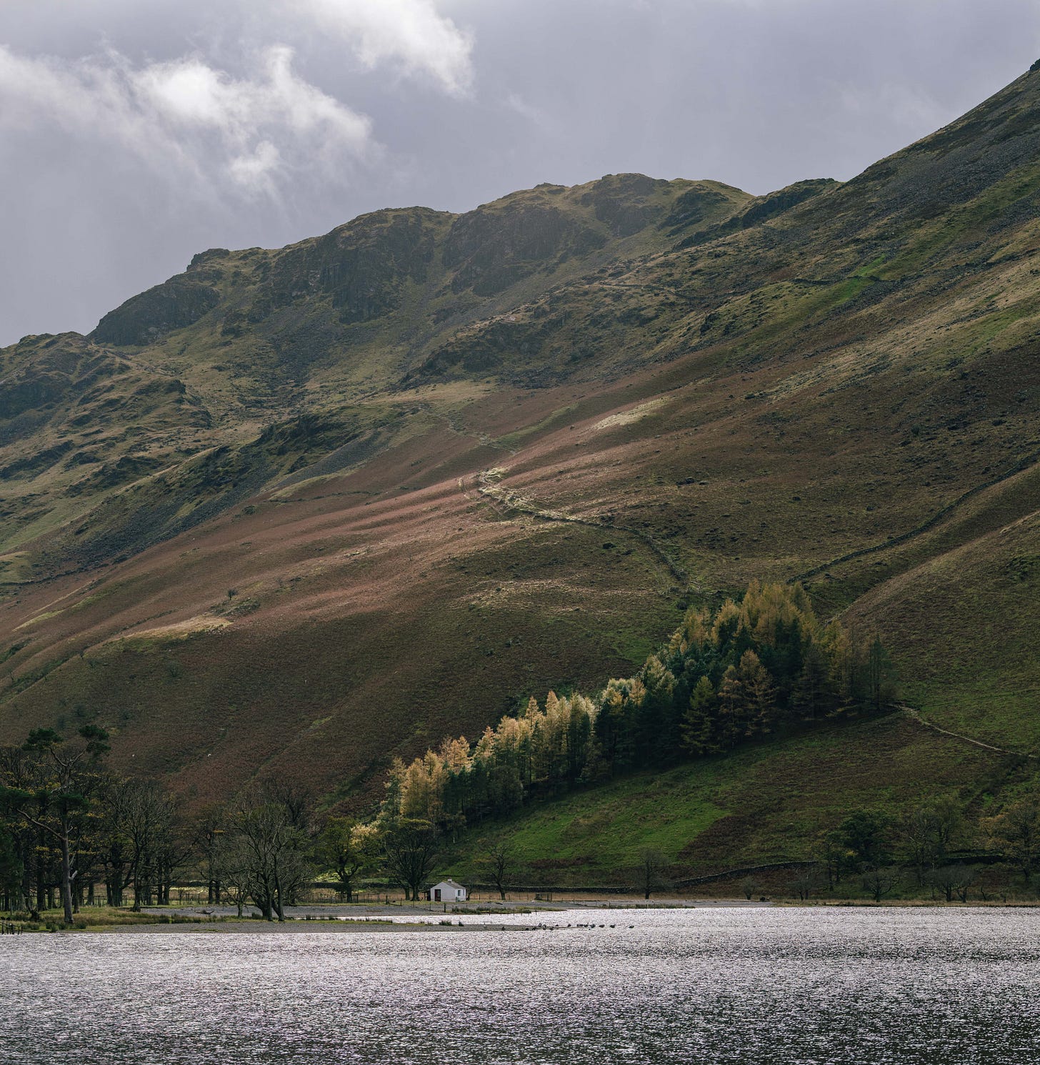 Hillside above Buttermere Lake in the Lake District, dramatic light breaking through clouds, rural Northwest England landscape Hillside above Buttermere Lake in the Lake District, dramatic light breaking through clouds, rural Northwest England landscape
