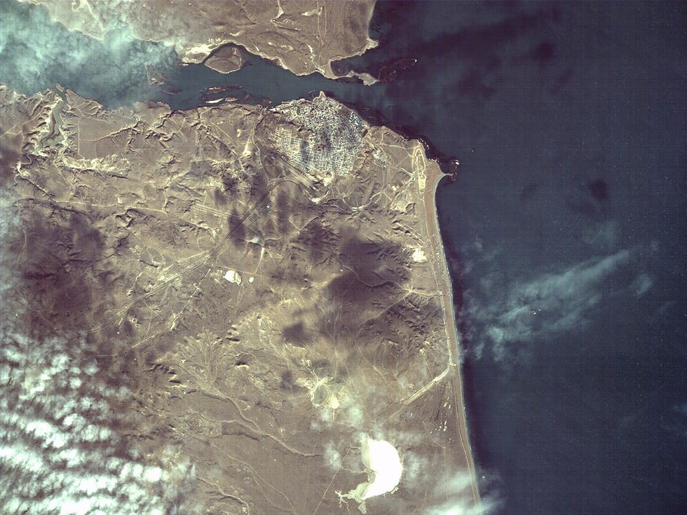 Satellite image of an arid coastal landscape with a small concentrated metropolitan area. Satellite image of an arid coastal landscape with a small concentrated metropolitan area.