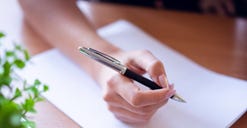 A woman writing with a pen. A woman writing with a pen.