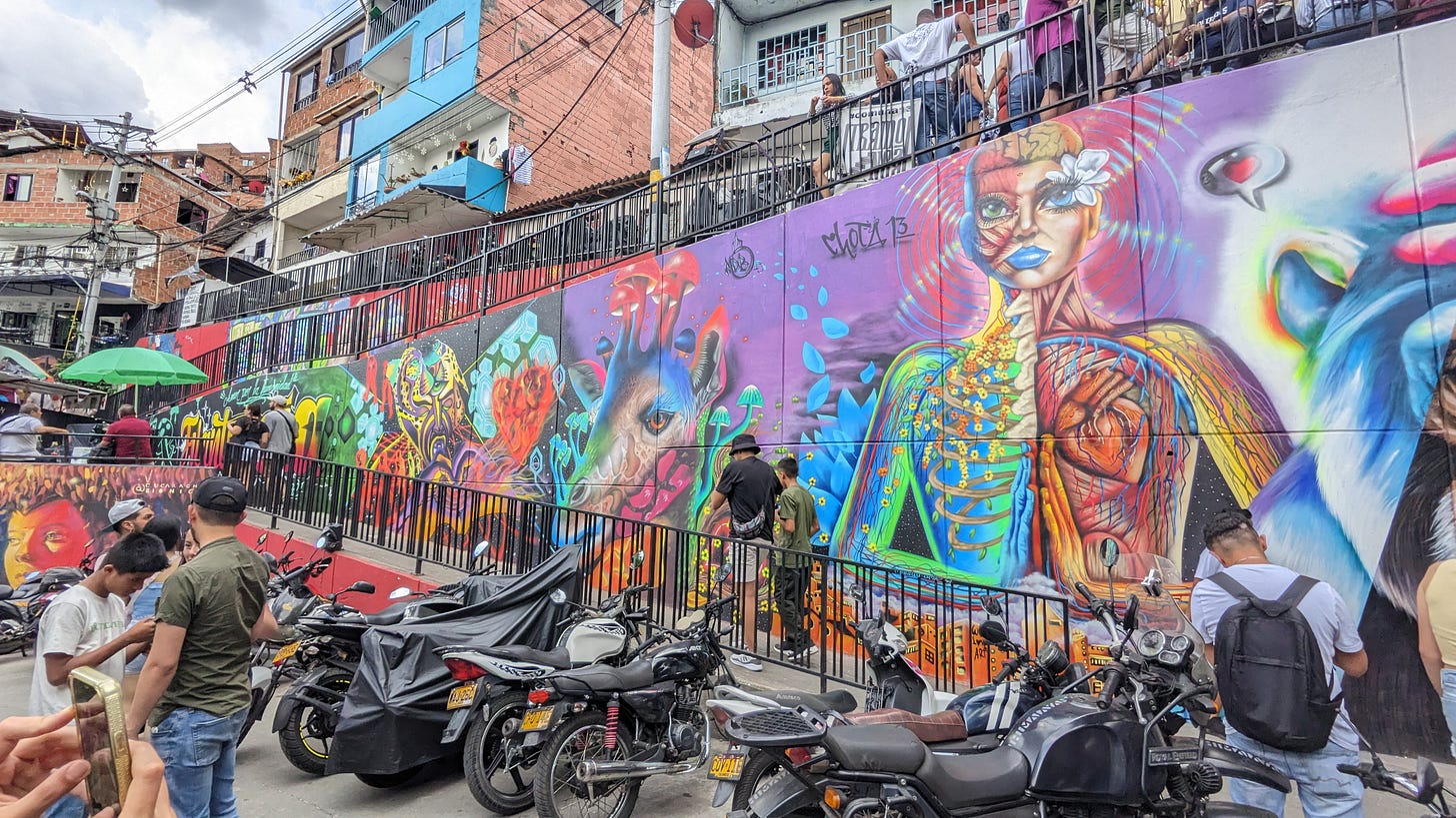 Several motorcycles parked in front of colorful graffiti in comuna 13 medellin