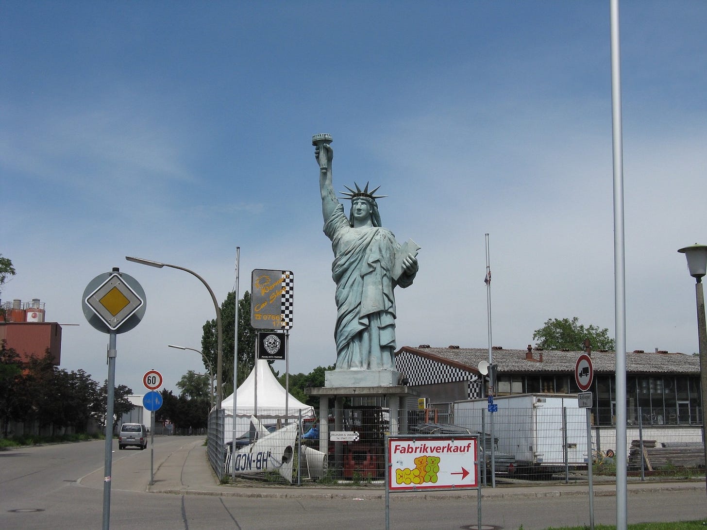 Stocky Statue of Liberty figure on street corner in light-industrial neighborhood