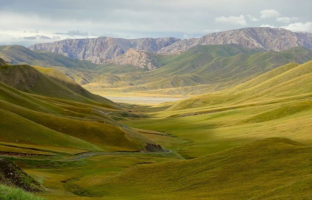 Rolling green hills meet distant mountains