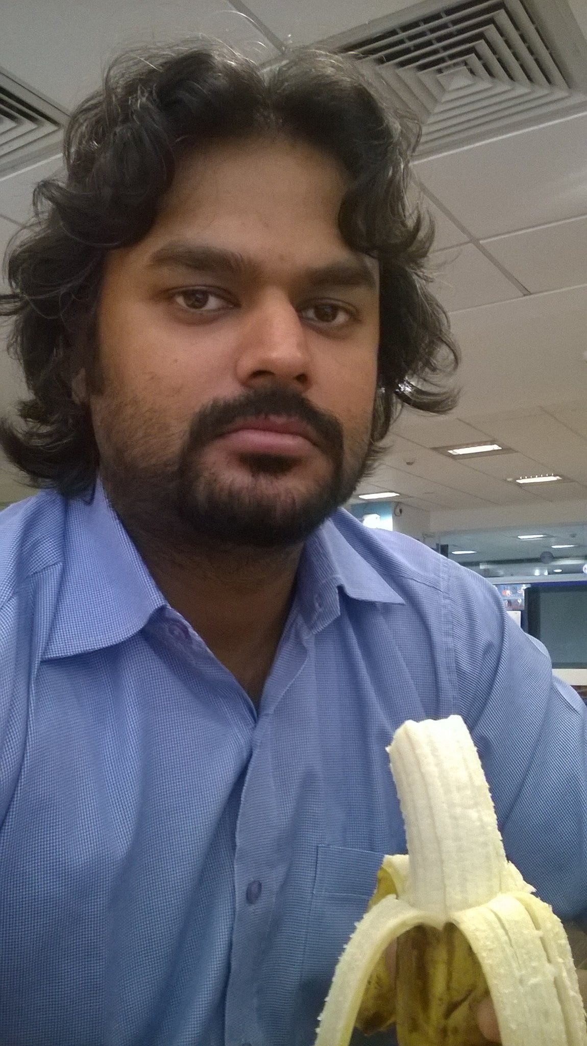 A man in an office eating a banana.