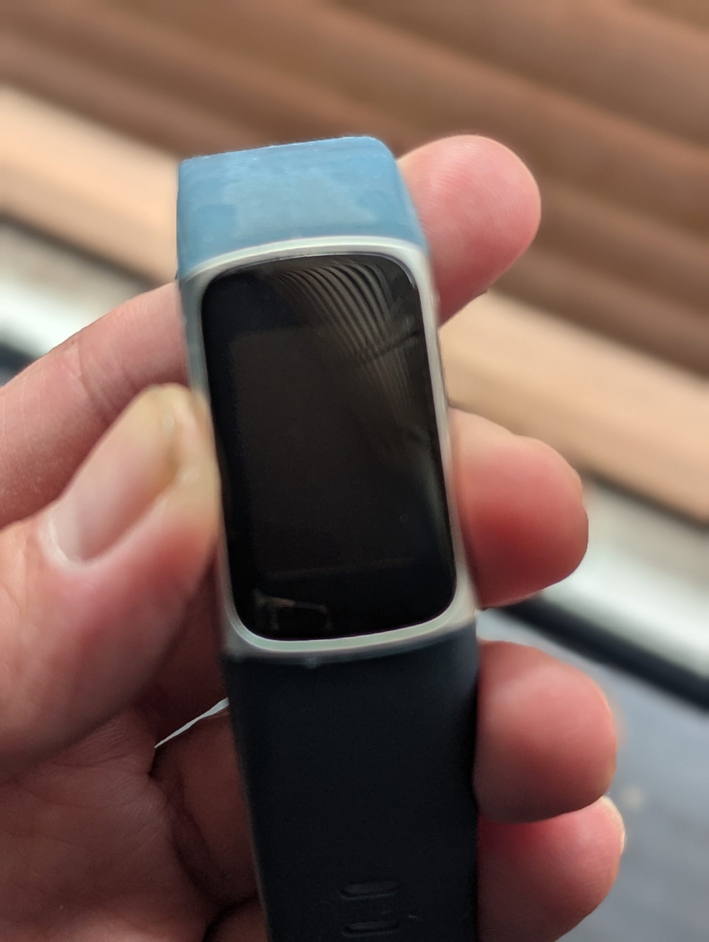 Dead Fitbit Charge watch being held near a window