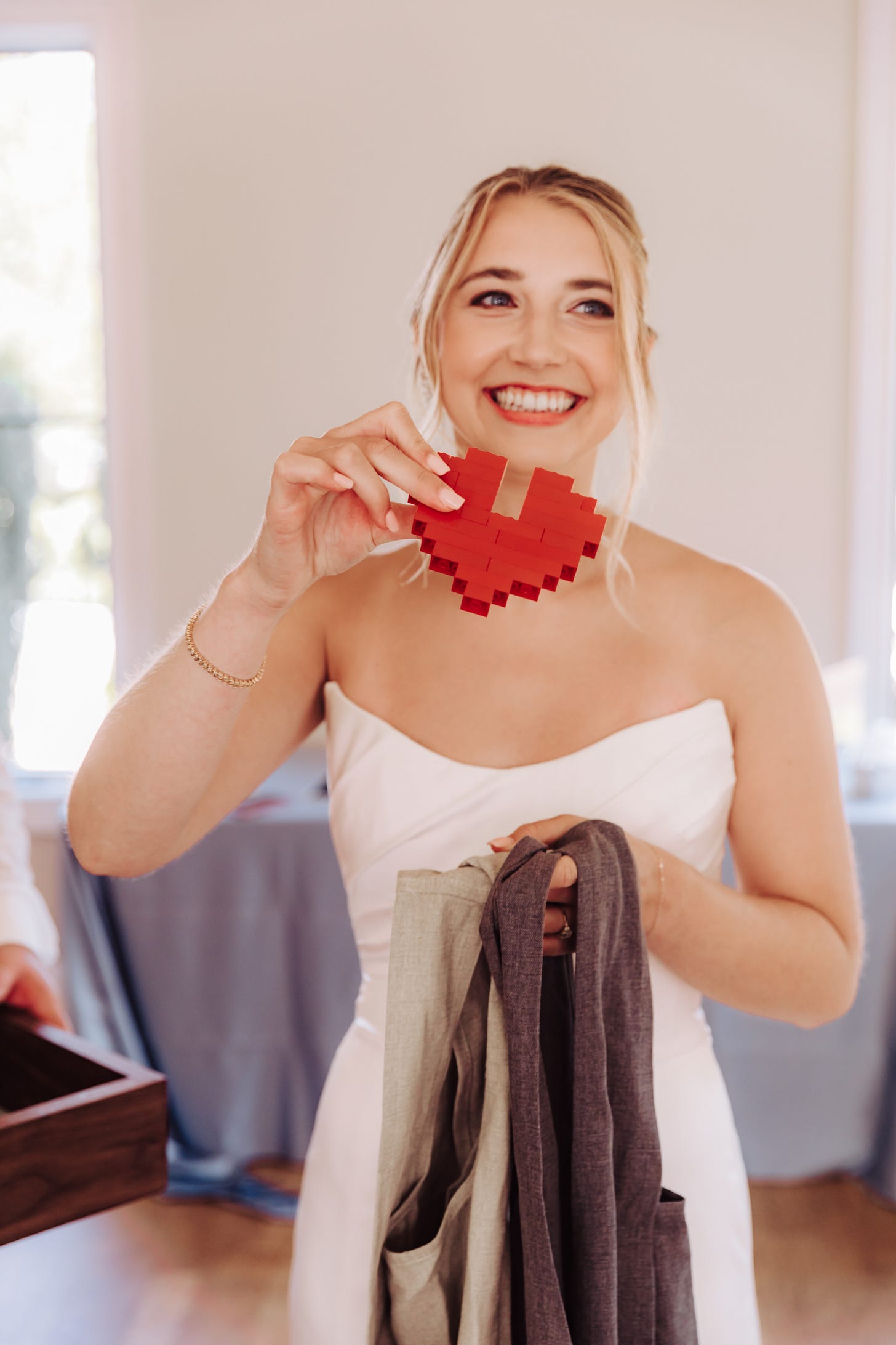 bride in dress with lego heart, aprons in hand, and a smile on her face. 