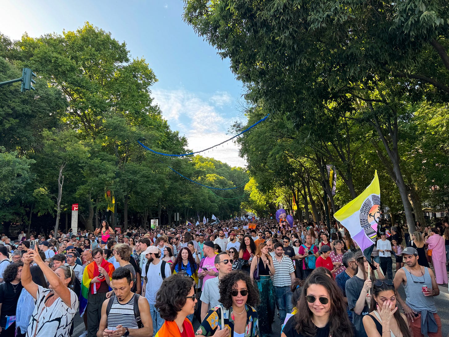A crowd fills a street underneath a canopy of trees. A crowd fills a street underneath a canopy of trees.