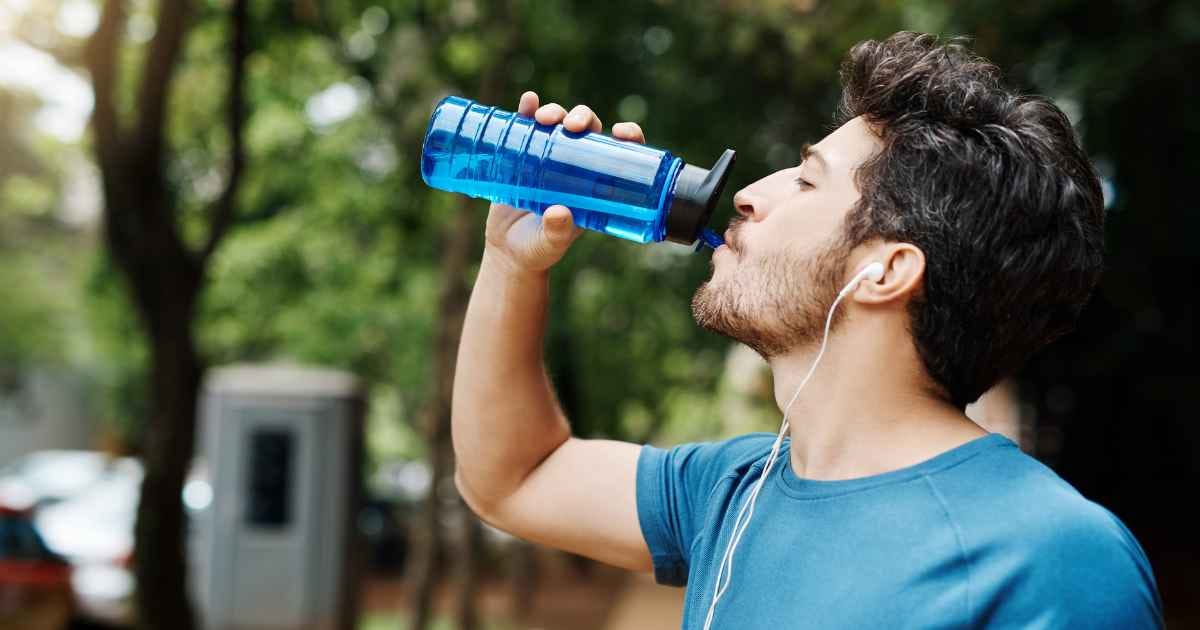 Man in a park drinking from water bottle