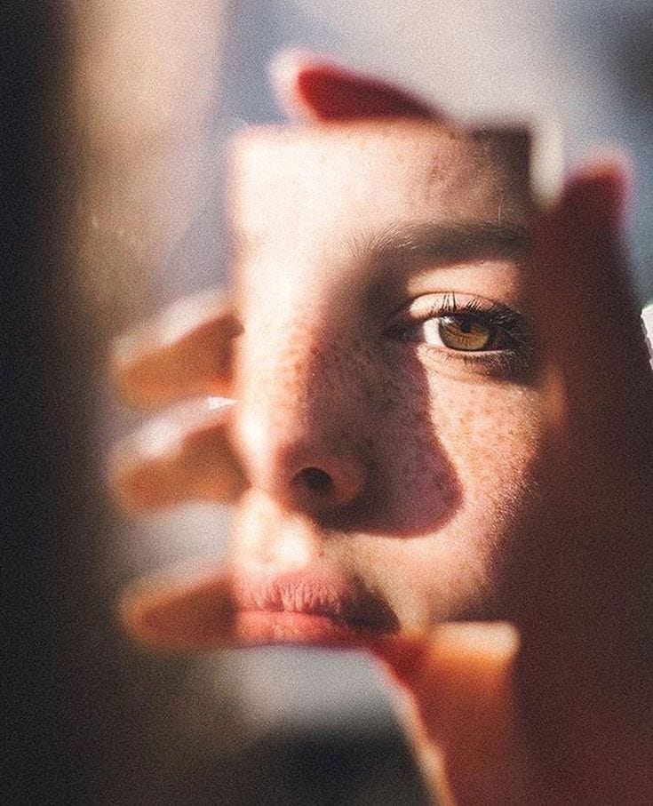 This may contain: a close up of a person holding a cell phone to their ear and looking in the mirror