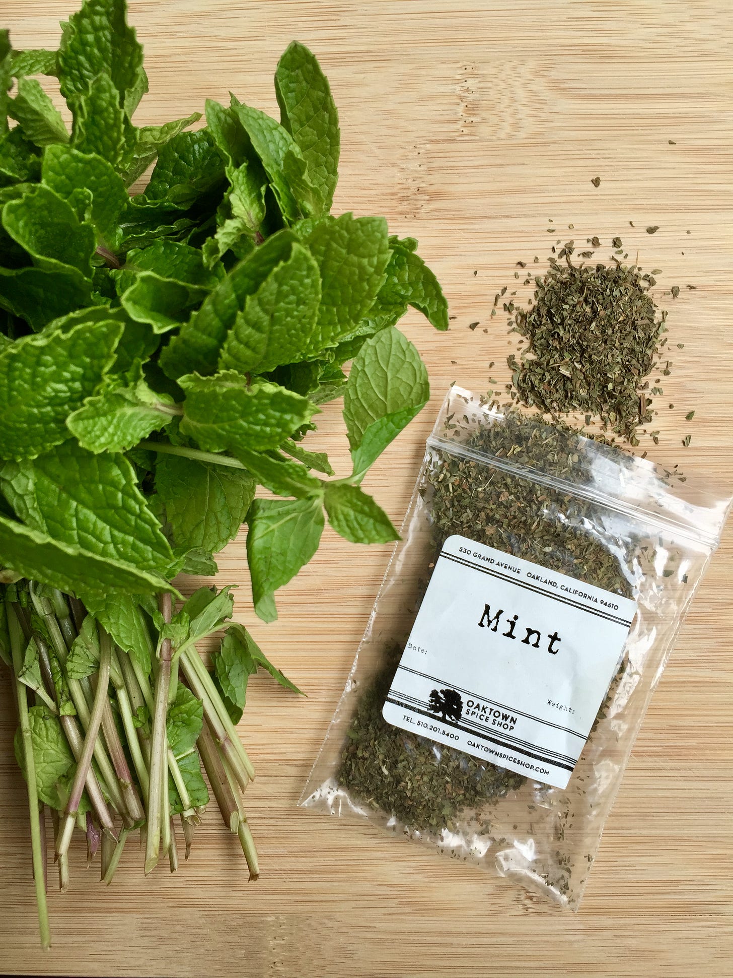 Fresh and dried mint on a wooden cutting board.