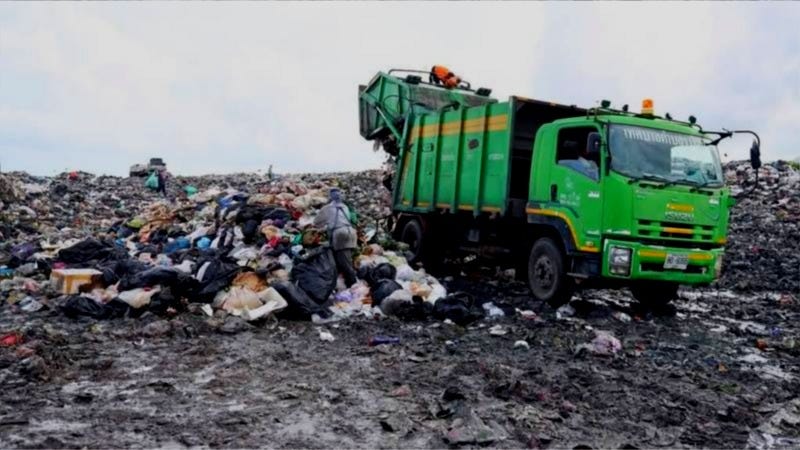 A green truck is unloading garbage at a landfill in Phuket, Thailand