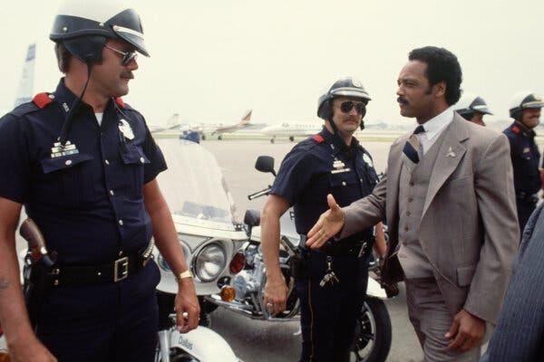 Jesse Jackson reaches out his hand to police officers.