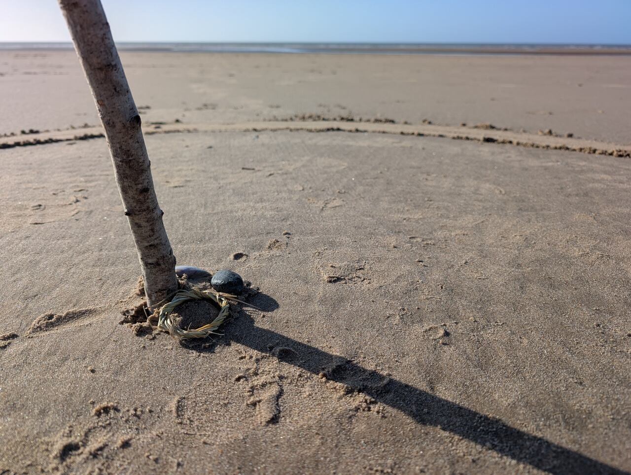 Shell, stone and a braid of marram grass in a ritual circle on the beach
