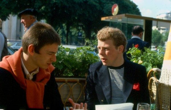 This may contain: two men are sitting at a table outside