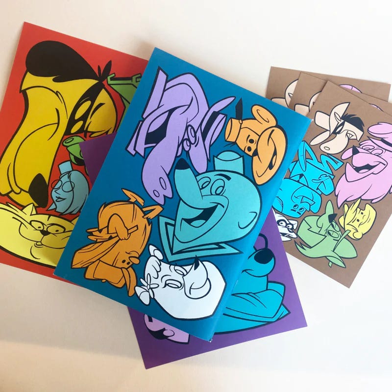 A collection of colorful zines featuring abstract, cartoon-style illustrations of various characters in bold, vibrant colors. The zines are displayed overlapping each other on a flat surface.