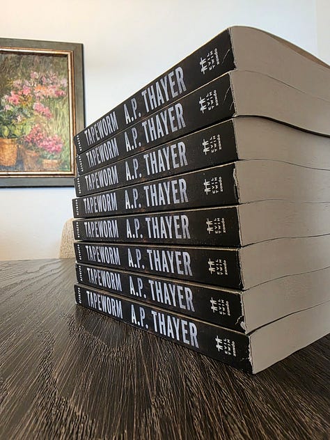 Paperback ARC stack of books, titled Tapeworm, by A.P. Thayer, a horror novel