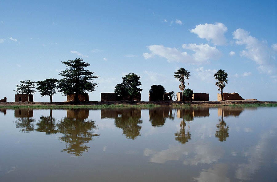 An image of the river Niger, overlooked by small houses and trees.