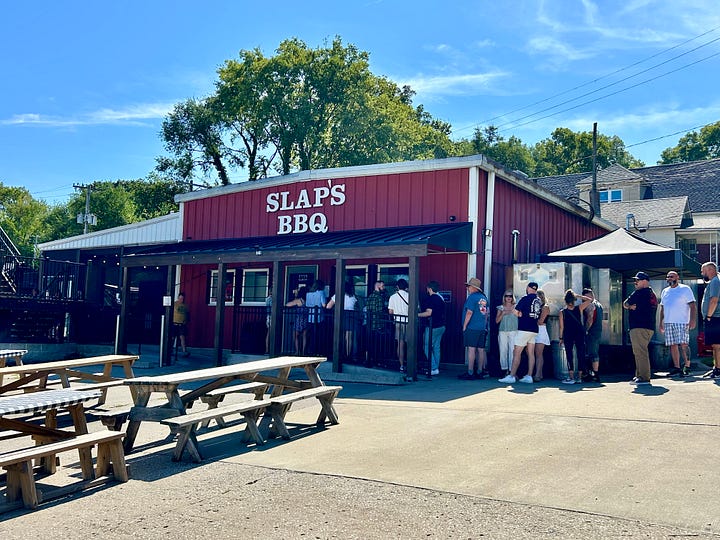 barbecue, picnic tables, signs, people in line