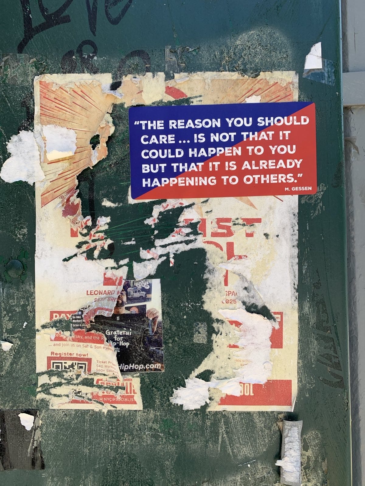 Image of a sticker on a green post office box, on top of other past stickers that have been torn off. The sticker reads, "THE REASON YOU SHOULD CARE...IS NOT THAT IT COULD HAPPEN TO YOU BUT THAT IT IS ALREADY HAPPENING TO OTHERS."