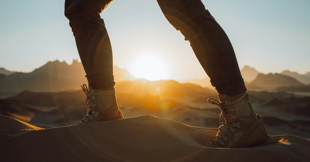 a person standing on top of a sand dune a person standing on top of a sand dune