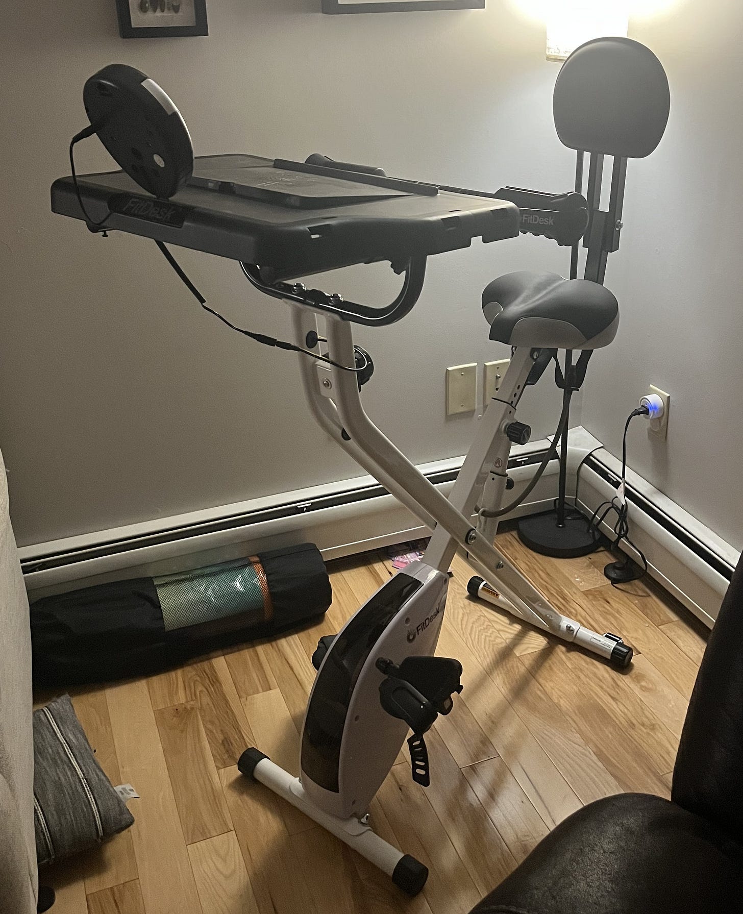 Aforementioned compact exercise bike set up in a corner against a light grey wall Aforementioned compact exercise bike set up in a corner against a light grey wall
