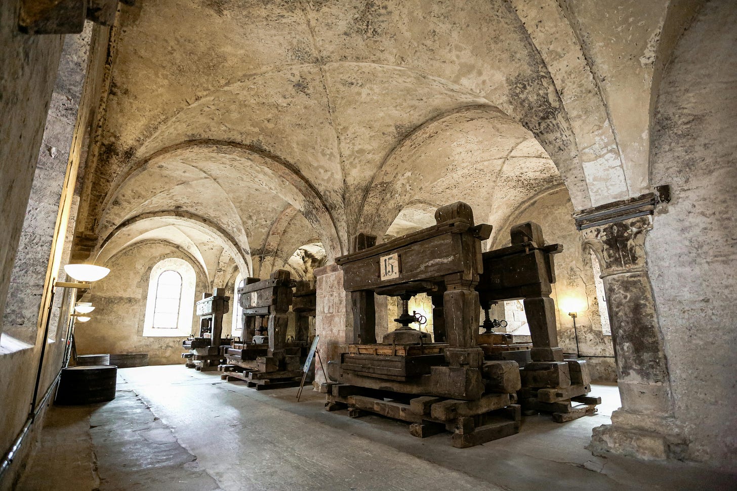 Stone monastery scriptorium with arched corridors and natural light, visual metaphor for gatekept knowledge in cybersecurity