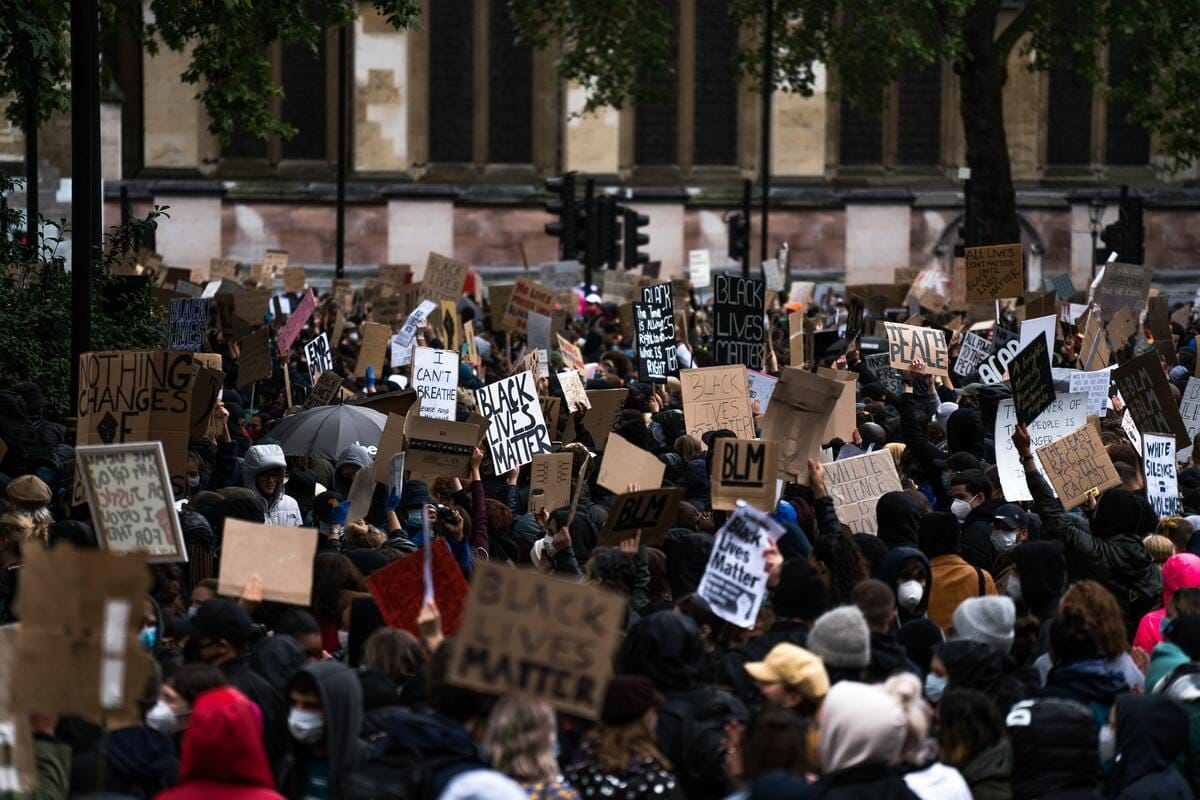 Depicts a street crowded with people and signs at a Black Lives Matter protest in London