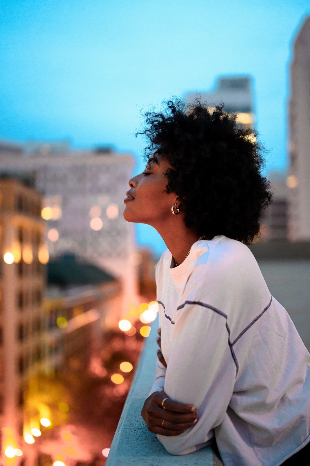 woman in white collared shirt looking at the city during night time woman in white collared shirt looking at the city during night time