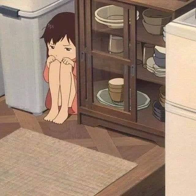 This may contain: a woman sitting on the floor in front of a cabinet with plates and cups next to it