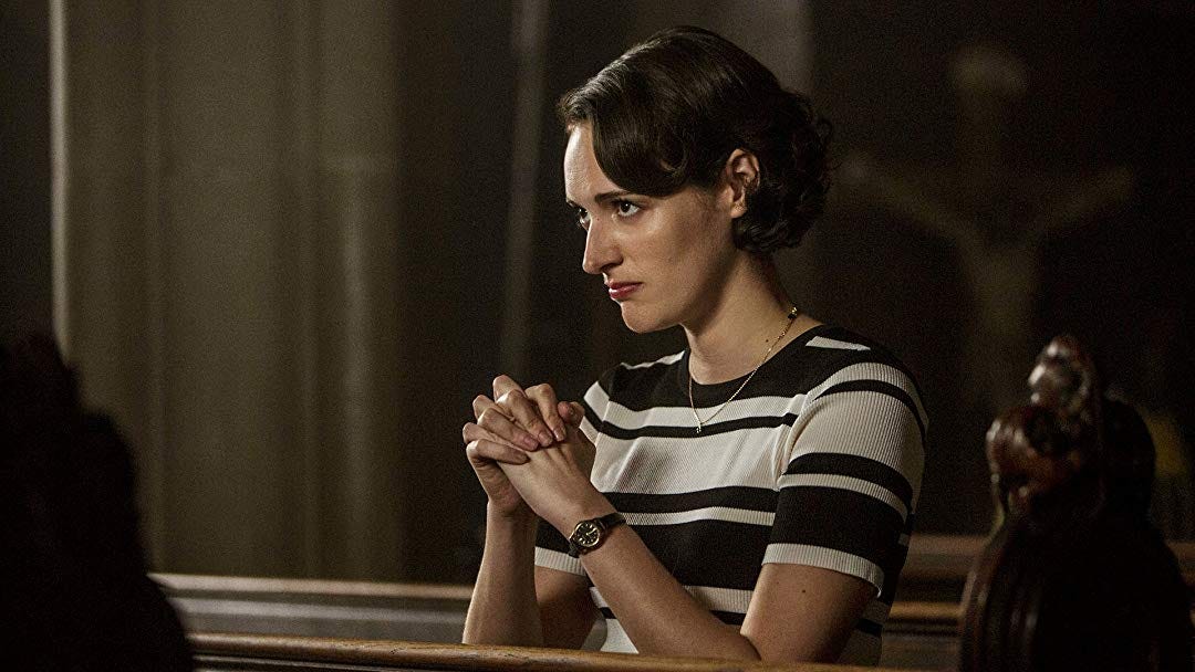 A woman with short brown hair, wearing a striped shirt and a necklace, prays while kneeling in a pew A woman with short brown hair, wearing a striped shirt and a necklace, prays while kneeling in a pew
