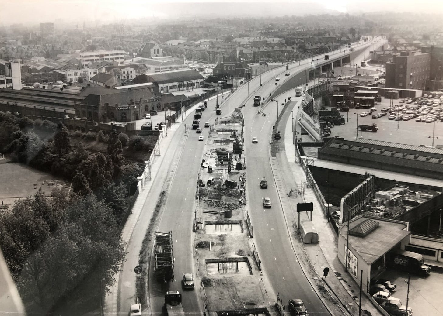 Black and white photograph, taken from a high vantage point, showing the Chiswick Flyover in its original form, with a ramp down to ground level. In the foreground work is happening in the middle of the A4 to build the viaduct to carry the future M4. Black and white photograph, taken from a high vantage point, showing the Chiswick Flyover in its original form, with a ramp down to ground level. In the foreground work is happening in the middle of the A4 to build the viaduct to carry the future M4.