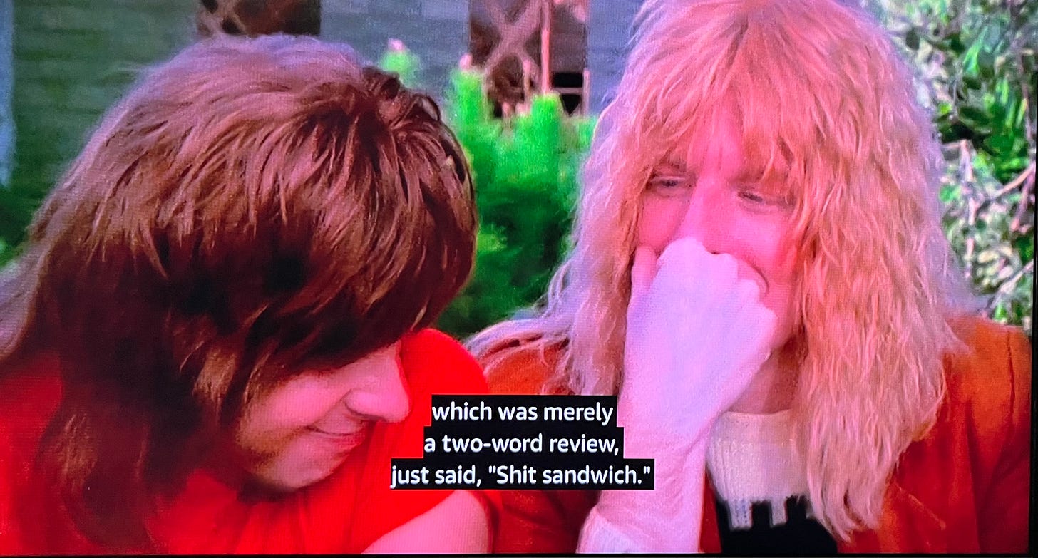 Image from This is Spinal Tap: Nigel and David are cracking up while Marty diBergi reads a review of their record Shark Sandwich, “which was merely a two-word review, just said, ‘Shit sandwich.’