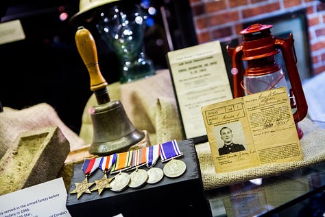 Photographs showing tin hats with 'Police' written on them, bullseye lamps, a hand bell, metal County Police signs and medals.