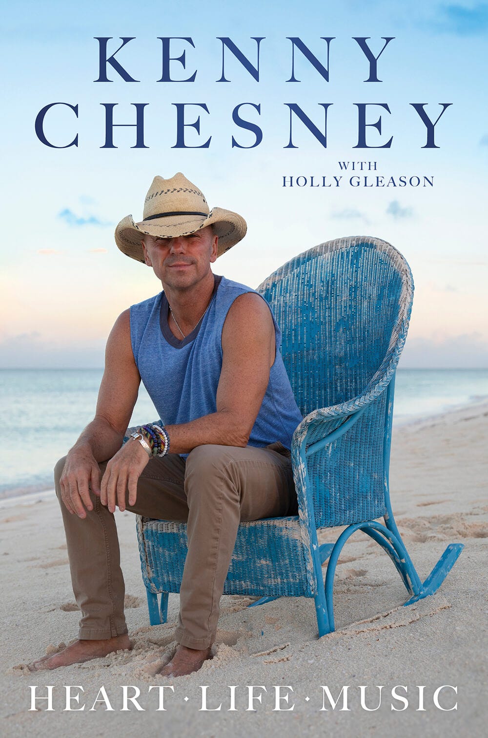 Kenny Chesney sitting on a chair by the beach, promoting his book.