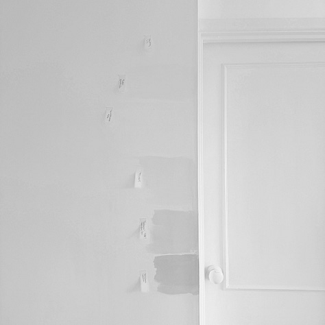 Photographs of a white door and wall with paint samples of different white paints with orange post it notes labelling the paint colours