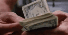 a person is holding a large stack of money in their hands . a person is holding a large stack of money in their hands .