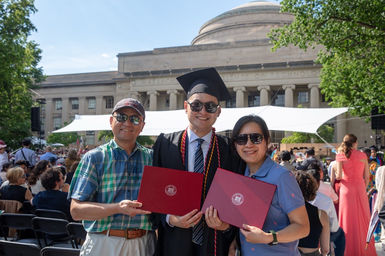 Junru in MIT graduation regalia holding two red diploma folders with two companions in front of the Great Dome Junru in MIT graduation regalia holding two red diploma folders with two companions in front of the Great Dome